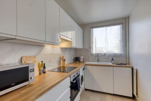 une cuisine avec des armoires blanches, un évier et un micro-ondes dans l'établissement Superb T4 close to the Stade de France (10 min), à Saint-Denis