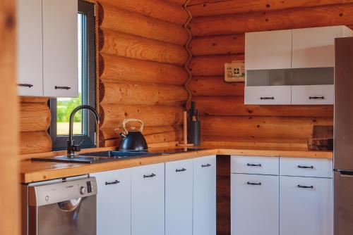 a kitchen with white cabinets and a sink at Domki nad jeziorem - Zalesie 7D in Zalesie