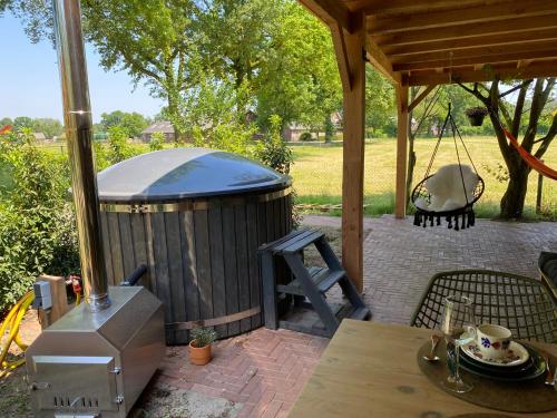 a gazebo with a table and a swing at Luxe lodge met hottub op het platteland in Dinxperlo