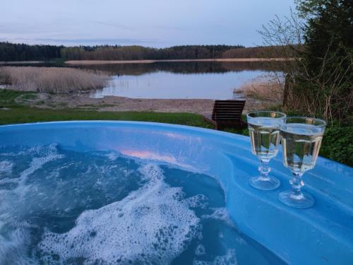 two glasses of water are sitting in a hot tub at Domki nad jeziorem - Zalesie 7D in Zalesie