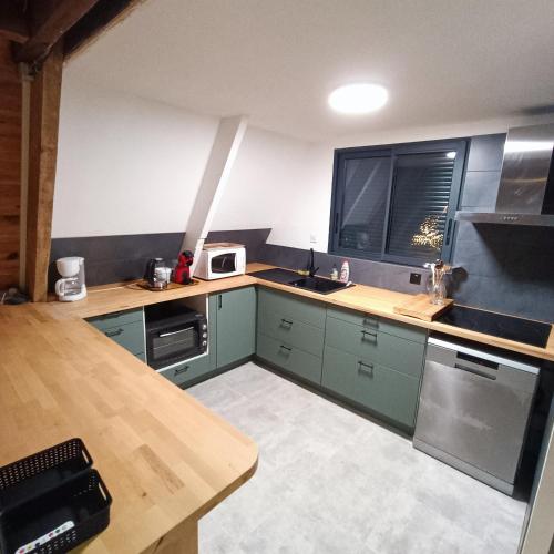 La cuisine est équipée d'armoires vertes et d'un four micro-ondes blanc. dans l'établissement CHALET- Vallée de LUCHON - Vallée DE LA PIQUE, à Cierp