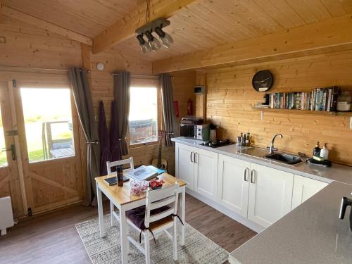 a kitchen with a table in a wooden cabin at Cosy cabin in Annie’s meadow in West Meon
