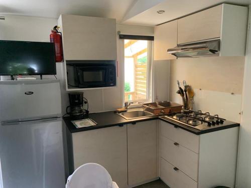 a small kitchen with a white refrigerator and a sink at Mobil-home Ouistreham in Ouistreham