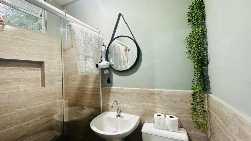 a bathroom with a sink and a mirror and a toilet at Pousada Casa Florinda in Teresópolis