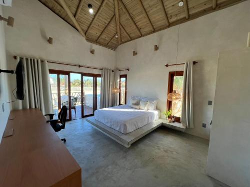 a bedroom with a bed and a desk and windows at Jurema Branca Villa in Beberibe