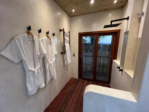 a bathroom with white shirts hanging on a wall at Jurema Branca Villa in Beberibe