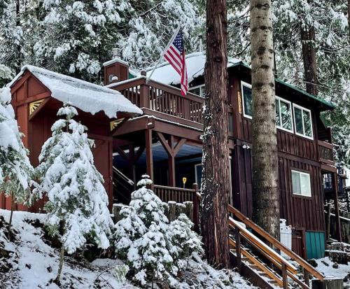 a log cabin in the snow with an american flag at Lewis Creek cabin near Yosemite king beds in Oakhurst