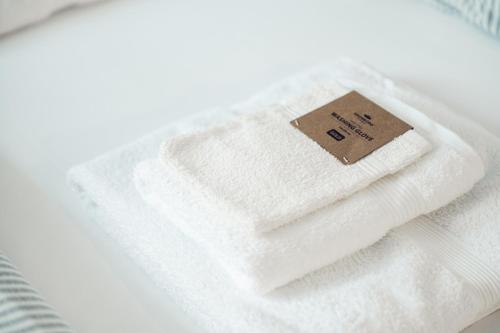 ein Stapel weißer Handtücher mit einem Schild drauf in der Unterkunft Axd DownTown Spacious Lux Apartment in Alexandroupoli