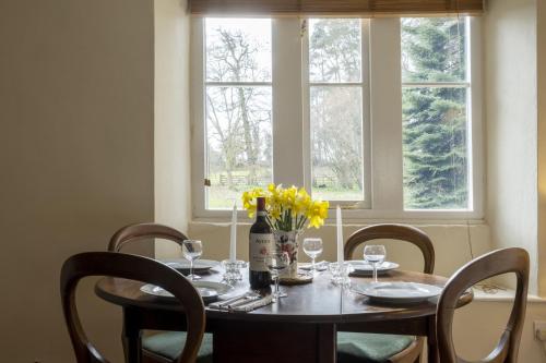 a table with chairs and a bottle of wine and flowers at Castle Lodge Haughton Castle in Hexham