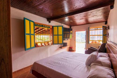 a bedroom with a large bed and two windows at Finca los Juanes in Jardin