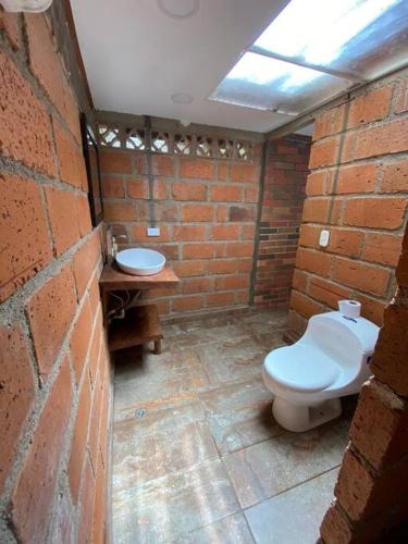 a brick bathroom with a toilet and a sink at Finca los Juanes in Jardin