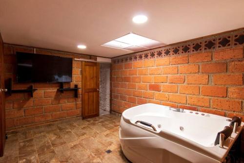 Zimmer mit einer Badewanne und einem TV an einer Backsteinwand in der Unterkunft Finca los Juanes in Jardin
