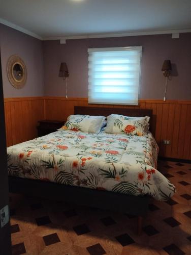 Una cama con edredón y almohadas en un dormitorio. en Cabañas Marina del Sur 1, en Puerto Natales