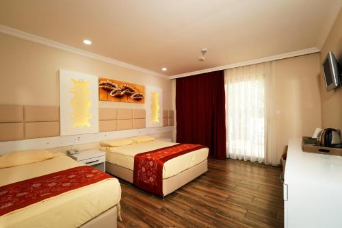a hotel room with two beds and a television at MIRAMOR HOTEL & Spa - ULTRA ALL INCLUSIVE SELECTION in Kemer