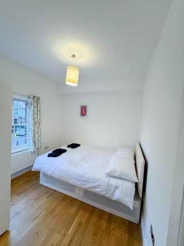 a white bedroom with a bed and a window at LA CASITA in Colindale