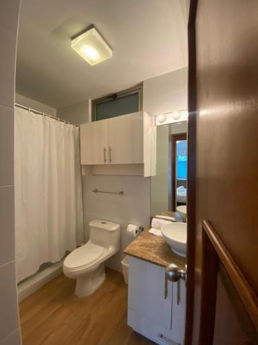 y baño con aseo blanco y lavamanos. en Apartamentos La Cañada en Guatemala
