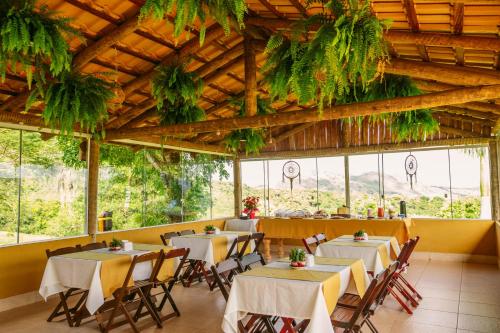 a restaurant with tables and chairs in a room with windows at Pousada Mirante dos Ipês - Capitólio - MG in Capitólio
