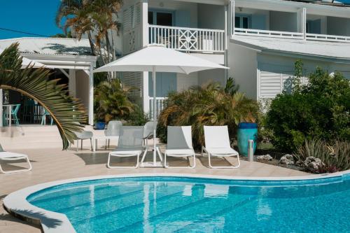 uma piscina com cadeiras e um guarda-sol ao lado de uma casa em Hôtel Amaudo em Saint-François