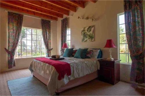 a bedroom with a bed and two windows at Lilly’s-place in Sabie