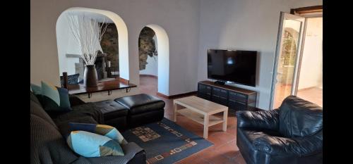 sala de estar con muebles de cuero y TV de pantalla plana en Casa Azuaje, en Moya