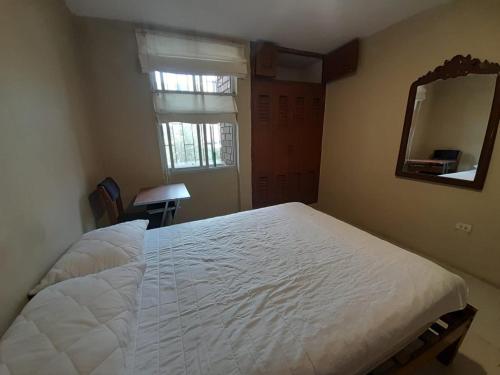 Schlafzimmer mit einem weißen Bett und einem Spiegel in der Unterkunft Departamento a un paso del Metropolitano y Miraflores in Lima