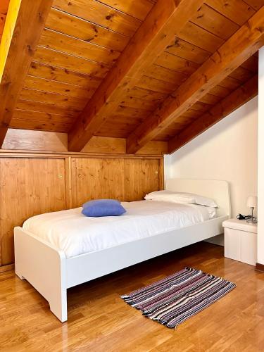 ein weißes Bett in einem Zimmer mit Holzdecke in der Unterkunft Ciàsa Mea in Calalzo