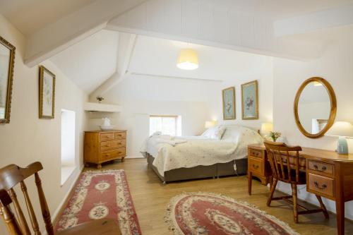 a bedroom with a bed and a desk and a mirror at White Lodge Haughton Castle in Hexham