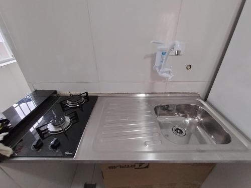 uma cozinha com um lavatório e um fogão em Suíte Studio 2 Enseada Tortuga Mobiliada no Guarujá