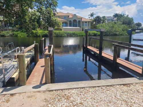 a dock in front of a house on a body of water at Iguana Updated Home By Large Imperial River 1 Mi to Beach in Bonita Springs