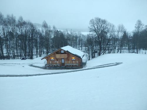 a log cabin in the snow with lights on at Family apartments V Zátiší in Dolní Morava