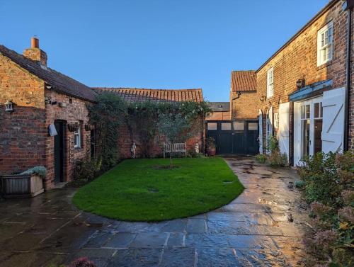 a courtyard with a lawn between two brick buildings at Skipton House Annex in Thirsk