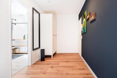a hallway with a blue wall and wooden floors at bee Apartments Design NESPRESSO Küche Parkplätze PS5 in Aachen
