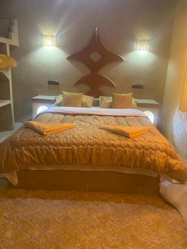 a bedroom with a large bed with orange sheets and pillows at Sunny Place apartments in Merzouga