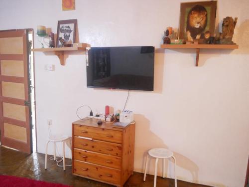 a room with a television on a wall with a wooden dresser at Masula Homes in Mombasa