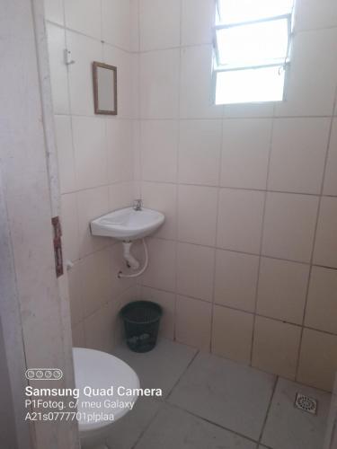 uma casa de banho branca com um lavatório e uma janela em Apartameto em Muriqui - RJ - Apto. 201 em Mangaratiba