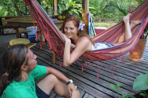 a girl sitting in a hammock with a man at Tree House Beachfront Lodge in Puerto Viejo