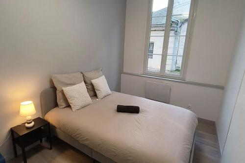 a bedroom with a bed with a lamp and a window at Appart proche palais justice in Angoulême