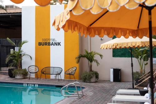 a hotel with a pool and chairs and an umbrella at Hotel Burbank in Burbank