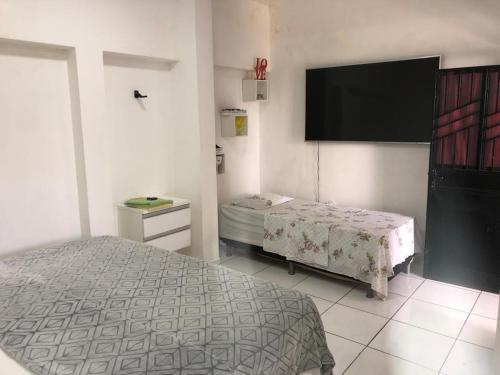 een slaapkamer met een bed en een flatscreen-tv bij Pousada das Flores. in Boa Vista