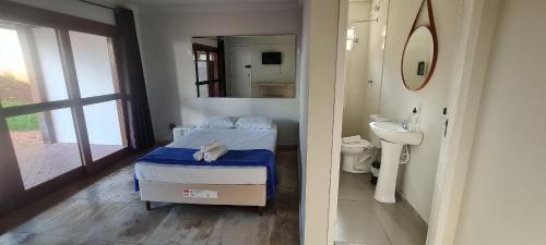 a bedroom with a bed and a sink and a mirror at Wafeh Pampulha Suítes in Belo Horizonte