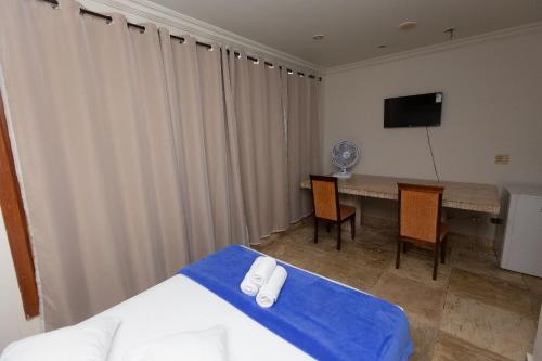 a room with a bed and a table and a television at Wafeh Pampulha Suítes in Belo Horizonte