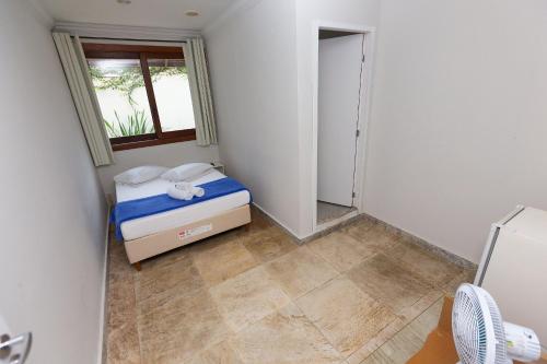 a small bedroom with a bed and a window at Wafeh Pampulha Suítes in Belo Horizonte