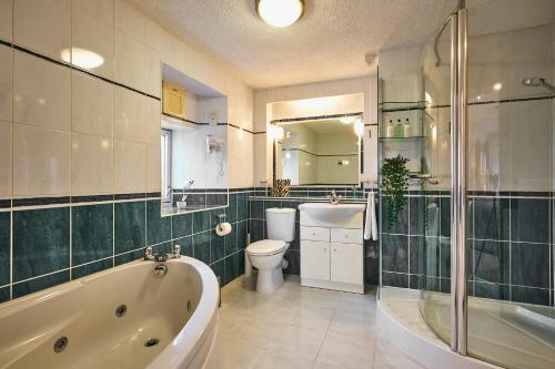 uma casa de banho com uma banheira, um WC e um lavatório. em The Old Stables - Hot Tub, Sauna and Cinema em Alyth