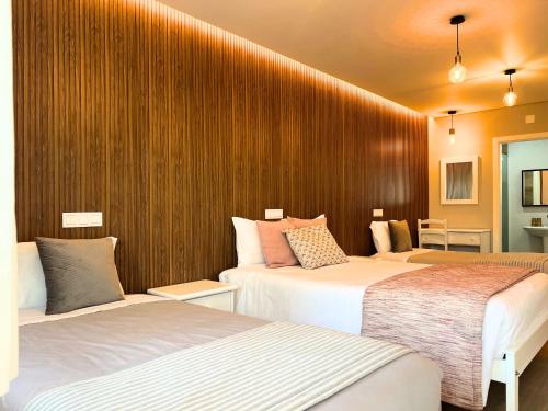 two beds in a hotel room with wood walls at Costa Brava Alojamento in Benedita