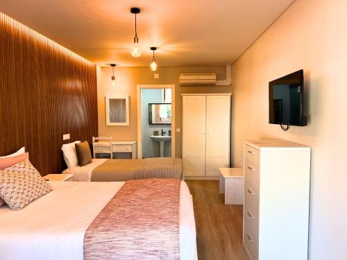 a hotel room with two beds and a television at Costa Brava Alojamento in Benedita
