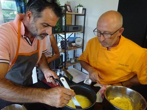 two men in a kitchen preparing food in a pan at VillAnolis Martinique in Le Carbet