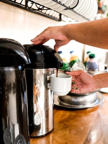 a person is pouring coffee into a coffee pot at HMG Rio Suítes in Rio de Janeiro