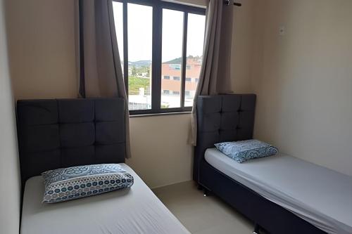 two beds in a room with a window at Apartamento em São Pedro 305 in Juiz de Fora