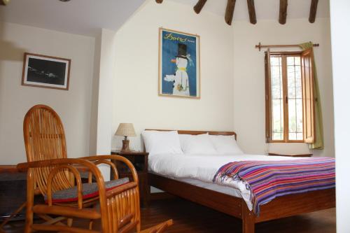 ein Schlafzimmer mit einem Bett, einem Stuhl und einem Fenster in der Unterkunft Maison Fortaleza in Cusco