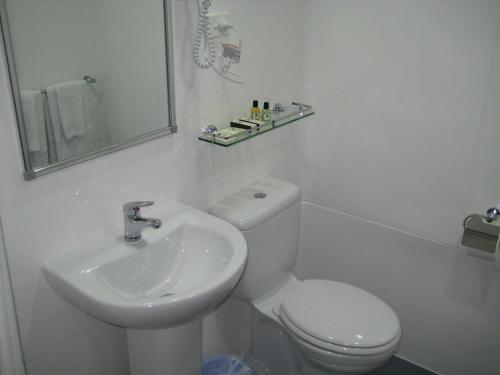 a white bathroom with a toilet and a sink at Devere Hotel in Sydney